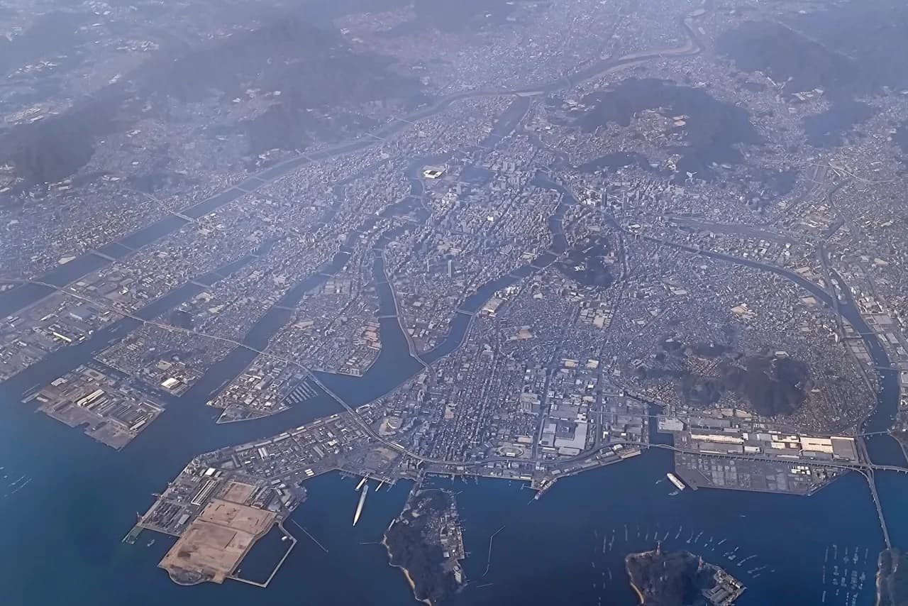 旅客機から見下ろした広島市街の航空写真。太田川の分流に挟まれた市街地が広島湾へ向かって広がり、周囲を山地が囲む