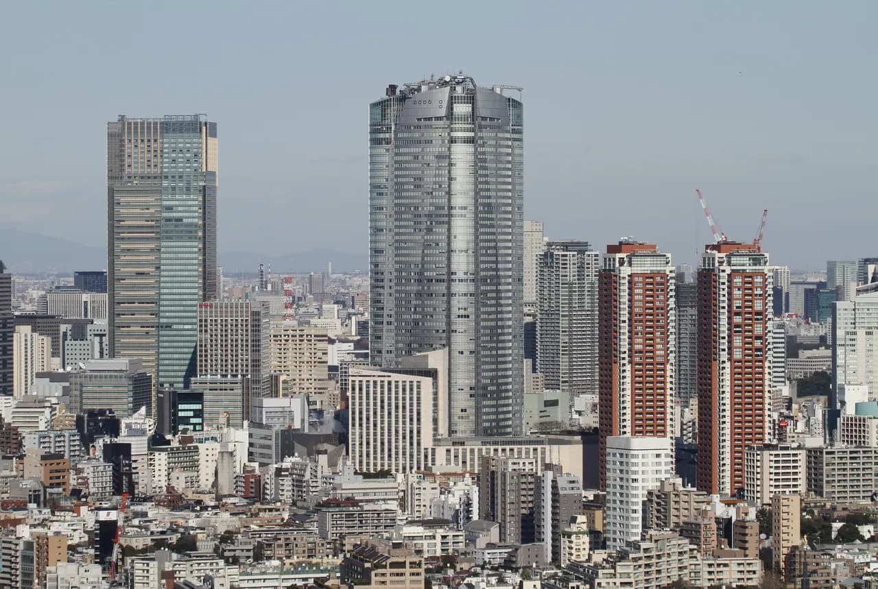 中低層の建物が密集する市街地の上にそびえる六本木ヒルズ森タワーと東京ミッドタウンの超高層ビル、手前に赤茶色の高層マンション