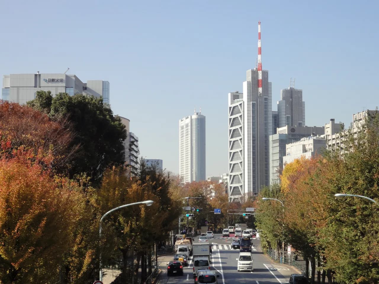 紅葉した街路樹が両側に続く外堀通りと、奥にそびえる高層ビル群。トラックや乗用車が行き交う晴れた日の通り