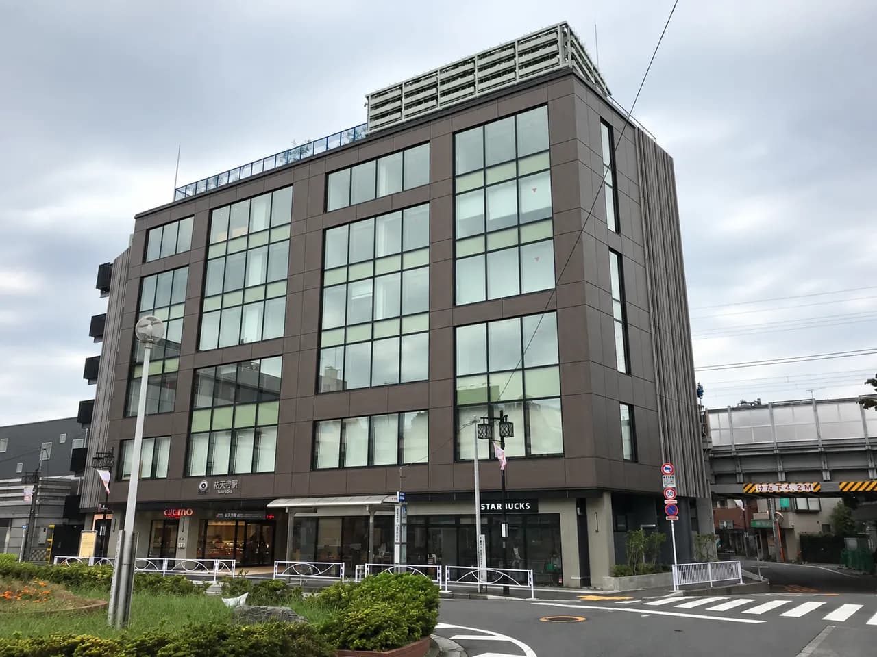 祐天寺駅東口の駅舎の街並み。建物と周囲の道路や植栽が見える