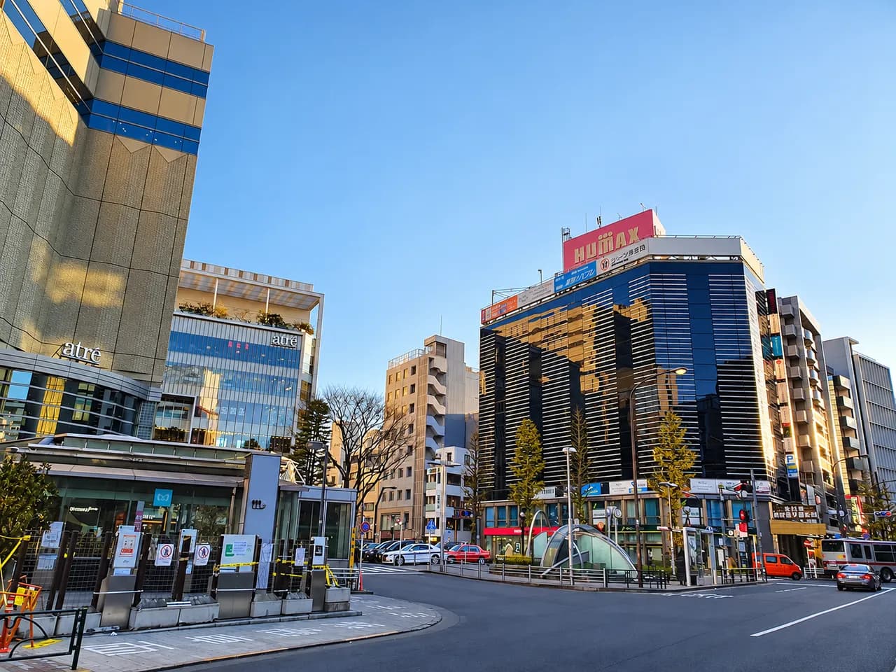 晴れた夕方の恵比寿駅西口。左に駅ビルのアトレ、中央にガラス張りのビルと地下鉄出入口のガラス屋根があり、ロータリーにタクシーや乗用車が並ぶ