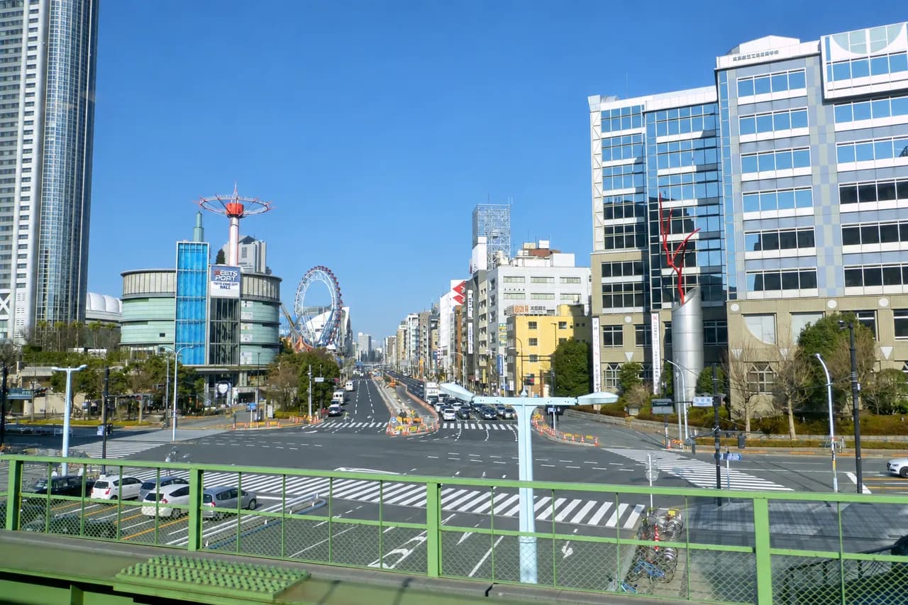 冬の晴天の下、白山通りの広い交差点と横断歩道。左に東京ドームホテルの高層ビルと円筒形の商業施設、右にオフィスビルが並ぶ