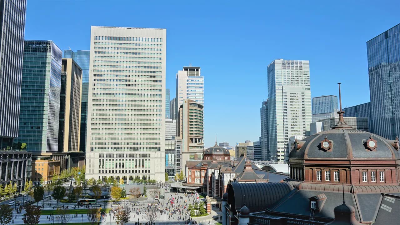 高い場所から見た東京駅丸の内側。右手前に赤れんが駅舎のドーム屋根、中央に駅前広場、奥に高層オフィスビルが並ぶ晴れた日の眺め
